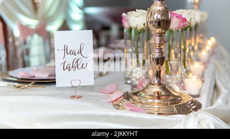 Un tavolo per una cerimonia di nozze con decorazioni di candele e fiori con un cartello Head Table Foto Stock