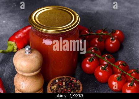Salsa di pomodoro dolce piccante con aglio, pepe ed erbe in vasetti di vetro. Pomodori in scatola in succo di pomodoro Foto Stock