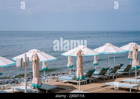 Ampia vista su fila di ombrelloni e sdraio da spiaggia durante il giorno d'estate, spazio per fotocopie Foto Stock