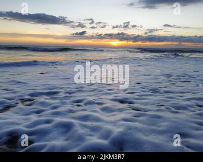 Un bellissimo scatto di tramonto sulle onde schiumose che colpiscono la riva di Philippine Beach Foto Stock