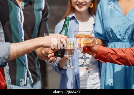 Primo piano di amici multietnici che si godono bevande all'aperto partito alla luce del sole Foto Stock