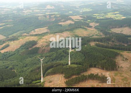 renania settentrionale vestfalia, Germania 9 luglio 2022 turbine eoliche che ruotano sulla cima di una collina verde Foto Stock