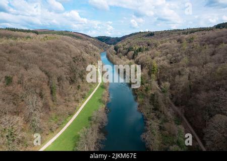 Una vista aerea di un fiume blu che scorre attraverso le foreste sotto un cielo nuvoloso e luminoso Foto Stock