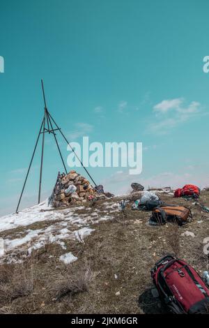 Uno scatto verticale della cima delle montagne di Yeranos, Armenia con gli zaini degli escursionisti sdraiati a terra sotto un cielo azzurro chiaro Foto Stock