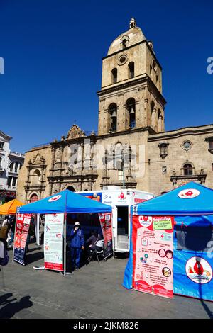 Plaza San Francisco, la Paz, Bolivia. 2nd agosto 2022. Un medico si trova accanto al centro di raccolta mobile dove le persone possono dare il sangue, un servizio organizzato dalle autorità sanitarie della città di la Paz. Le banche del sangue della Bolivia si affidano molto alle donazioni di volontari e centri di raccolta come questo sono comuni nella città, soprattutto durante i periodi di vacanza o quando ci sono carenze. Dietro si trova la chiesa di San Francisco, la più importante e suggestiva chiesa coloniale della città. Foto Stock