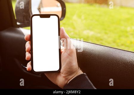 Passeggero maschio in auto che tiene il dispositivo smartphone con schermo mockup vuoto come spazio copia Foto Stock