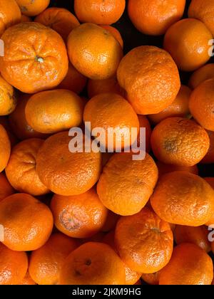 Uno scatto verticale di molte arance insieme sotto la luce Foto Stock