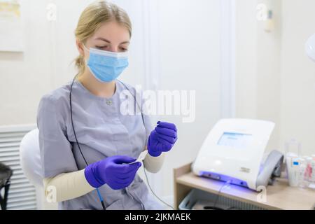 primo piano delle mani del maestro dell'elettrolisi in cui tiene un ago per rimuovere i capelli indesiderati Foto Stock