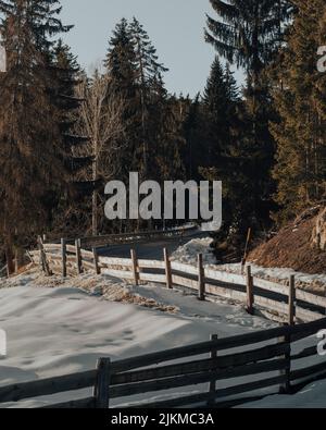 Una strada tortuosa a fianco di una montagna con ringhiera in legno durante l'inverno Foto Stock