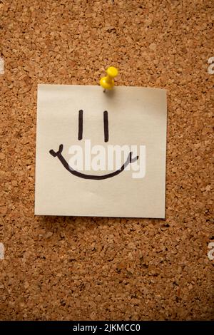 Una foto verticale di un volto sorridente su un foglietto adesivo allegato Foto Stock