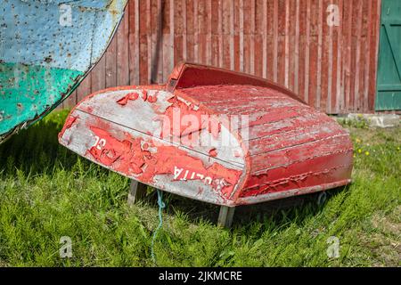 Vecchio peschereccio di legno rosso con vernice da peeling sulla terra a Sisimiut, Groenlandia, il 16 luglio 2022 Foto Stock