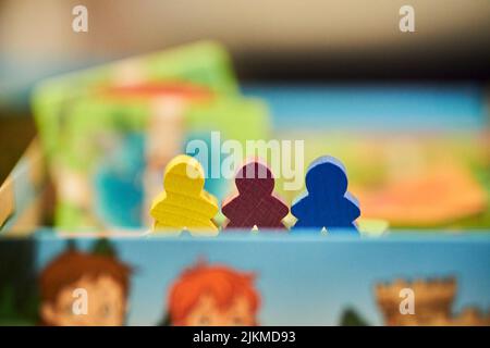 Un primo piano di pezzi colorati in legno all'interno di una scatola di un gioco Carcassonne. Foto Stock