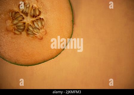 Singola fetta di cantalupo su fondo di terracotta arancione vista dall'alto metà di melone Foto Stock