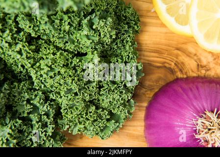 Mazzo di cipolla fresca biologica di kale rosso e limone su sfondo nero scuro. Foto Stock
