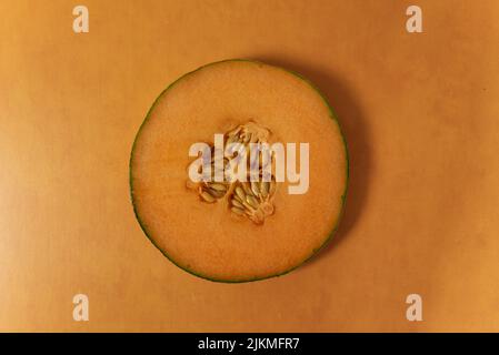 Singola fetta di cantalupo su sfondo arancione terracotta vista dall'alto del melone Foto Stock