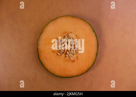 Singola fetta di cantalupo su sfondo arancione terracotta vista dall'alto centro Foto Stock