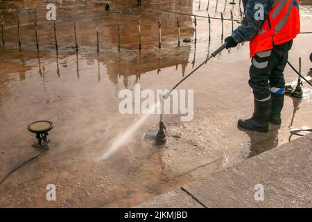 Un uomo utilizza una idropulitrice elettrica per una idropulitrice. Pulizia delle fontane della città in autunno. I lavoratori rimuovono lo sporco che si è depositato durante la s. Foto Stock