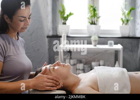 massaggio viso con olio in stile tradizionale realizzato da donne di bellezza professionisti. massaggio anti-età Foto Stock