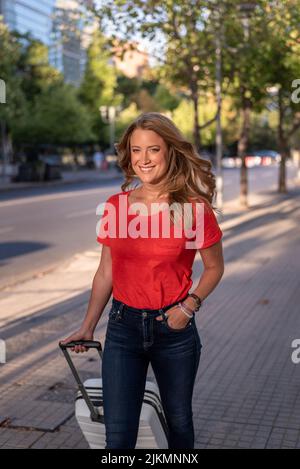 Un primo piano verticale di una donna caucasica che cammina per la strada di Santiago con una valigia, Cile Foto Stock