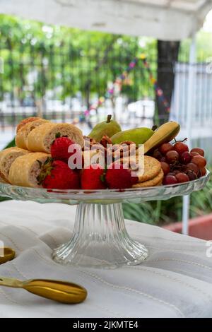 Cesto di frutta in vetro, Piccinc all'esterno. Vegetazione fuori fuoco sullo sfondo. Foto Stock