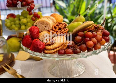 Cesto di frutta in vetro, Piccinc all'esterno. Vegetazione fuori fuoco sullo sfondo. Foto Stock