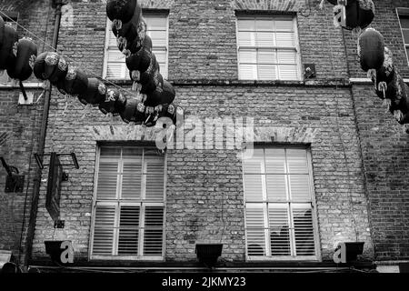 Un basso angolo in scala di grigi dell'edificio di China Town con Lanterne e carte appese decorate, Londra, Regno Unito Foto Stock