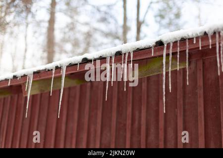 Un primo piano di un Icicle appeso al tetto rosso Foto Stock