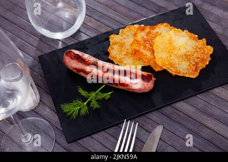 Frittelle di patate con fritto frankfurter su tavola di ardesia Foto Stock