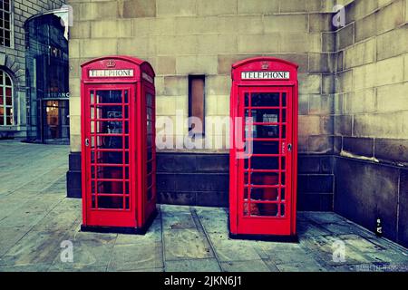 Cabine telefoniche rosse tradizionali vicino alla parete dell'edificio a Manchester, Regno Unito Foto Stock