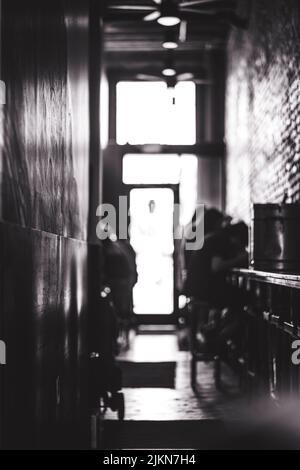 Una foto verticale in scala di grigi di persone sedute in un bar del ristorante con pareti o riflettenti Foto Stock