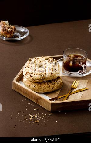 Un primo piano di una tazza di tè e pane fresco bagel rotola con semi su una tavola Foto Stock