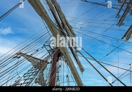 L'alto albero di una vecchia nave a vela con una scala a fune sullo sfondo blu del cielo Foto Stock