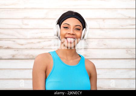 Ritratto di una allegra donna afroamericana che indossa abbigliamento sportivo e cuffie. Foto Stock