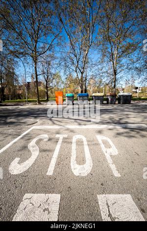 Uno scatto verticale di una strada con la segnaletica stradale di arresto e gli alberi in una città Foto Stock