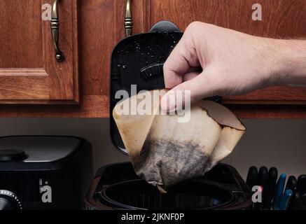 Persona che scarda il filtro usato dal cestello della macchina per il caffè Foto Stock