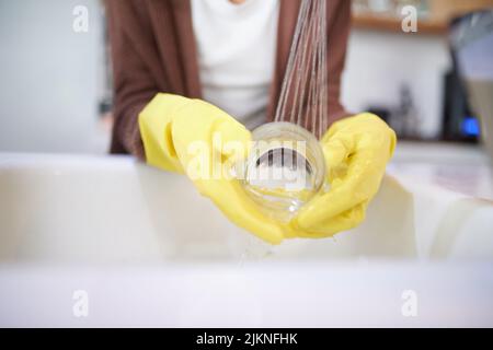 Non basta lavare, sciacquare, una donna irriconoscibile che lava i piatti a casa. Foto Stock