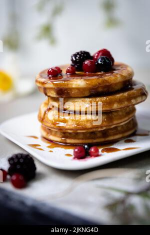 Un primo piano di frittelle impilate con sciroppo e bacche Foto Stock