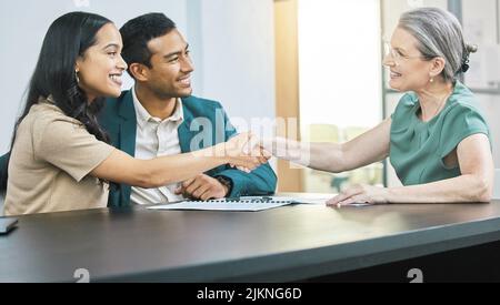Le vostre finanze sono in buone mani. Una giovane coppia che passa sopra un certo lavoro di ufficio durante un incontro con il loro consulente finanziario. Foto Stock