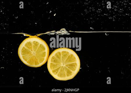 Le fette di limone spruzzi d'acqua, isolate su sfondo nero Foto Stock