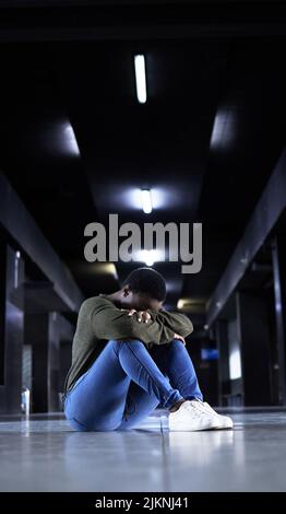 La shes aveva abbastanza. Scatto a tutta lunghezza di una giovane donna che guarda depressa mentre si siede sul pavimento di un terminal della stazione ferroviaria. Foto Stock