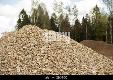 Sabbia sul cantiere. Il materiale di costruzione è accumulato in heap. Creare le basi per la strada. Foto Stock