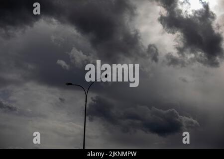 Palo di luce contro il cielo. Paesaggio celeste in tempo nuvoloso. Minimalismo dell'ambiente urbano. Foto Stock