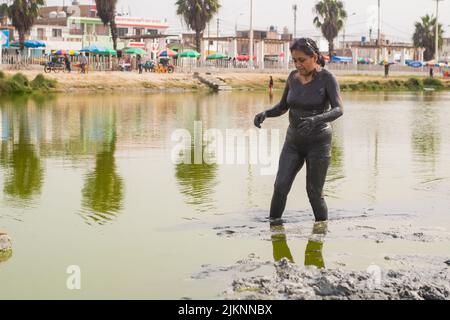 Un primo piano di una donna latina che fa fangoterapia all'aperto, in una laguna naturale Foto Stock