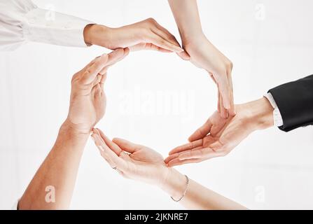 Dobbiamo stare insieme. Inquadratura a basso angolo di un gruppo di uomini d'affari che uniscono le mani in una formazione circolare. Foto Stock