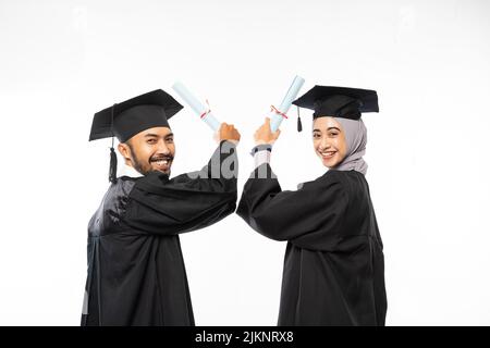 Due studenti laureati in possesso di un certificato mentre si guarda indietro Foto Stock