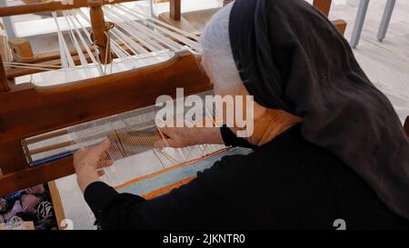 Un primo piano di una donna anziana che lavora con il telaio di tessitura Foto Stock