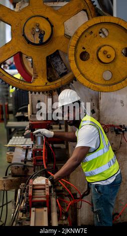 Heavy Industry Foreman Engineer ware giubbotto di sicurezza manutenzione preventiva giornaliera macchina di controllo in fabbrica di produzione, utilizzare appunti, hanno discussione Foto Stock