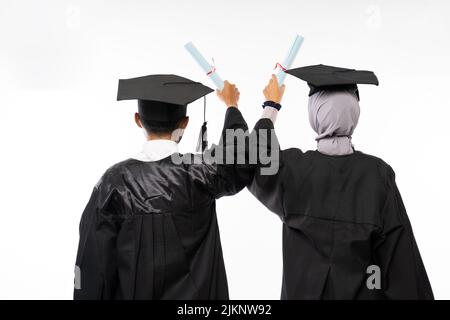 Vista posteriore di due studenti laureati in possesso di diplomi Foto Stock
