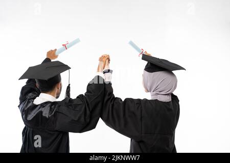 Due studenti laureati che tengono le mani e tengono il certificato Foto Stock