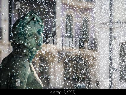 Una dozzina di gocce d'acqua che spruzzano sulla statua femminile con un volto premuroso Foto Stock